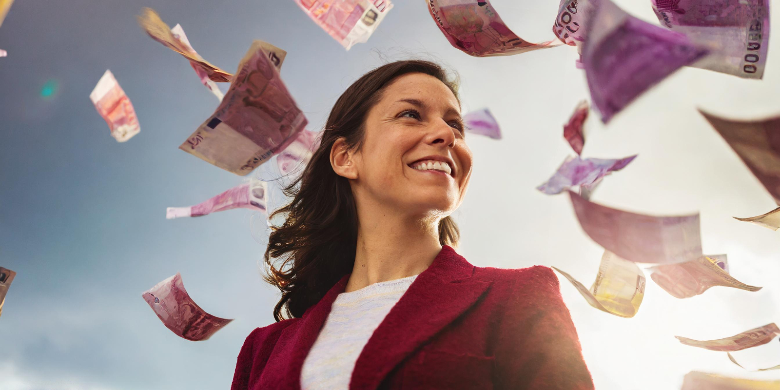entrepreneure souriante qui regarde les billets tomber du ciel